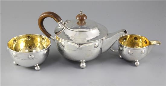 A George V Arts & Crafts silver three piece tea set by Albert Edward Jones, gross 15 oz.